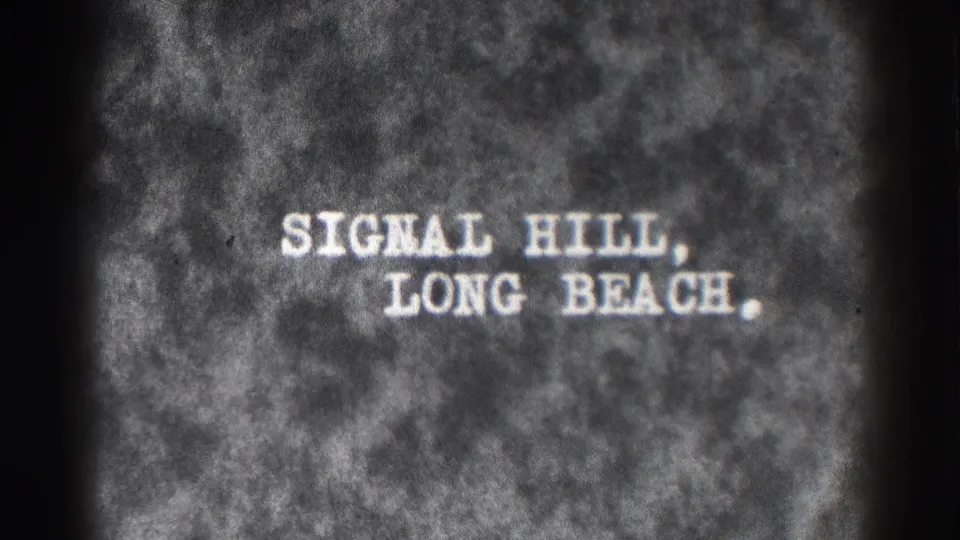 1937 8mm title card for Signal Hill, Long Beach, shown in white lettering on a mottled black-and-white film background.