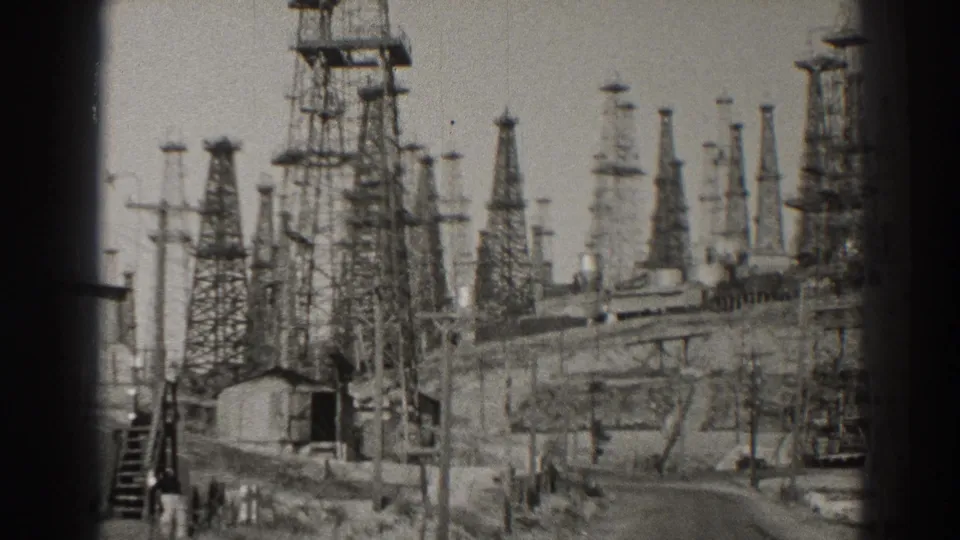 1937 Long Beach power-station frame showing an open service road bordered by towers, tanks, poles, stairs, and utility structures.