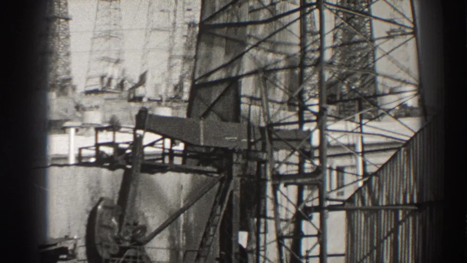 1937 Long Beach industrial frame showing the pumpjack counterweight and walking beam among railings, scaffolding, and tank surfaces.