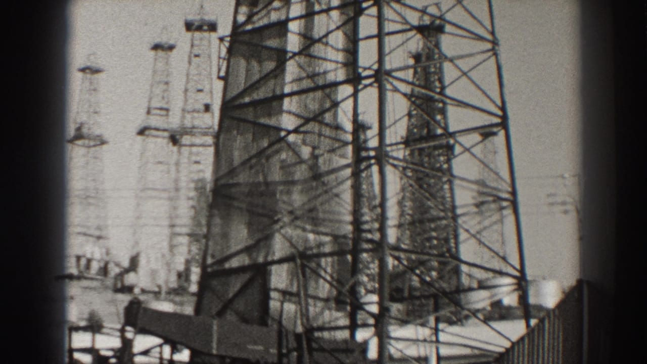 Tall oil derricks with lattice frames against a pale sky.