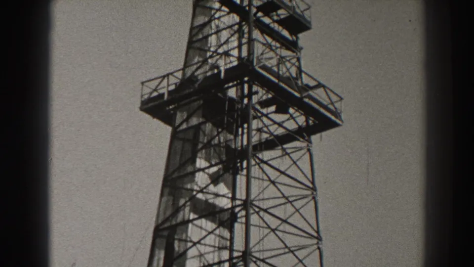 1937 Long Beach home-movie frame showing the upper portion of a tall metal lattice tower with railings and platforms.