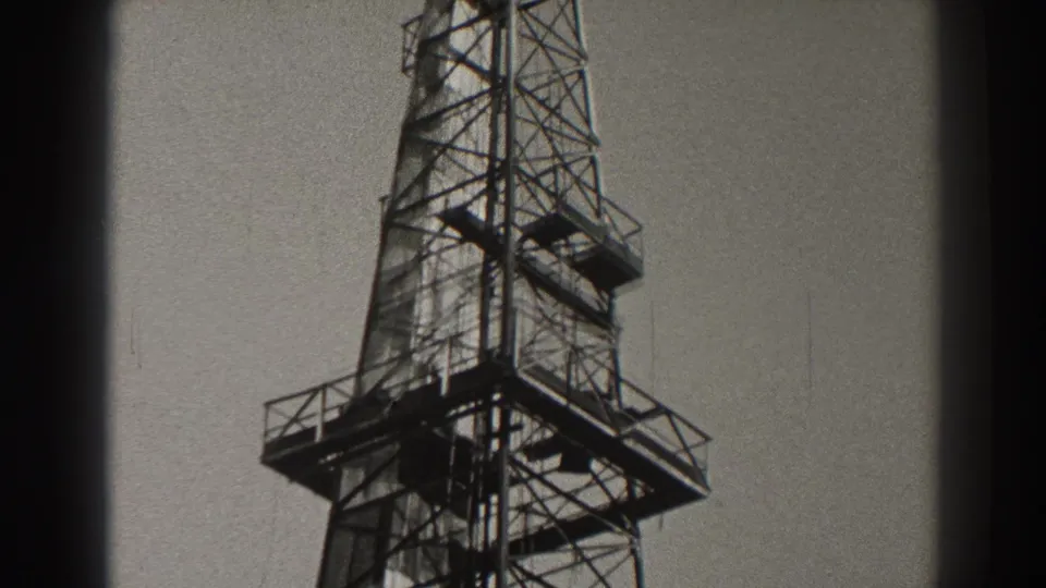 1937 Long Beach frame with a cropped view of the tower's metal bracing, elevated platform, and railings against open sky.