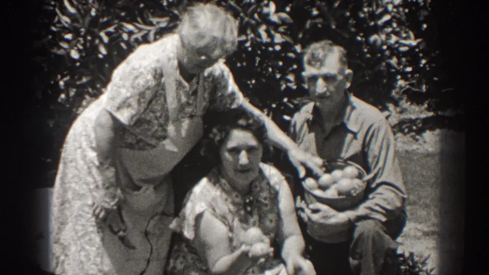 The family group gathers closely in a Long Beach garden, with fruit in hand and a basket held by the man.