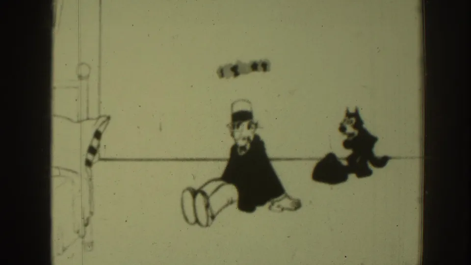 1937 8mm cartoon frame showing a seated top-hatted man and black cat near a small dark mound, with film edge shadows.