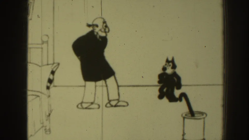 1937 8mm frame showing the top-hatted figure near a black cat character and a cylinder-like prop in a Felix the Cat cartoon sequence.