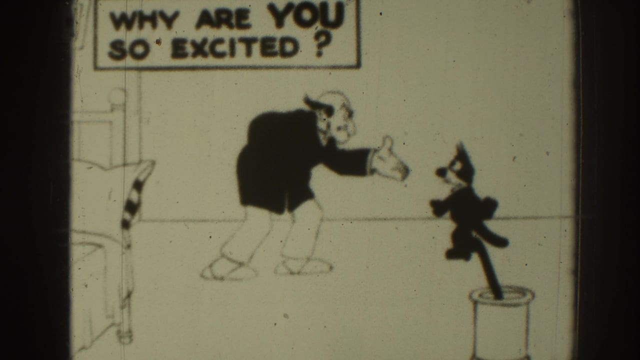 1937 8mm frame of a black-and-white cartoon with a suited animated man, small cat, bed edge, cylindrical stand, and question sign.