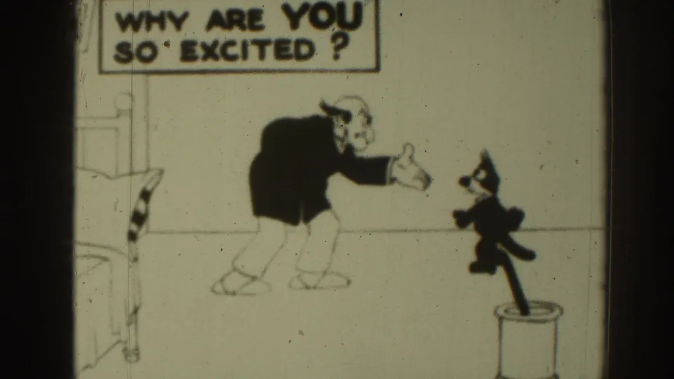 1937 8mm frame of a black-and-white cartoon with a suited animated man, small cat, bed edge, cylindrical stand, and question sign.