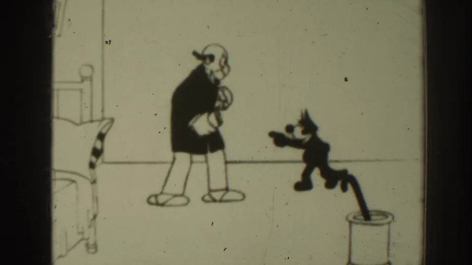 1937 8mm black-and-white cartoon frame showing a small cat character gesturing toward an animated man near a bed.