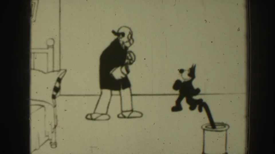 1937 8mm frame of a vintage black-and-white cartoon with a suited man watching a small cat-like figure in motion.