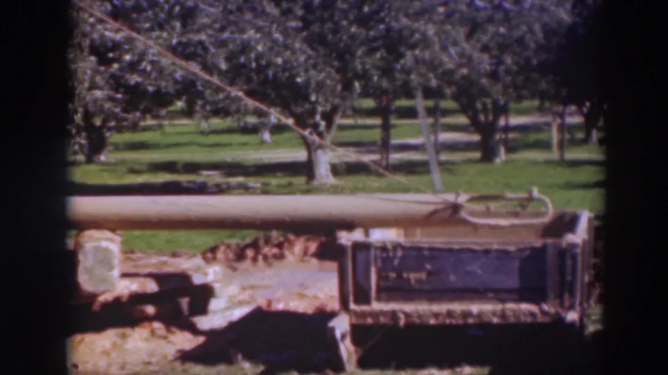 1937 Sacramento 8mm frame showing the wooden beam and rope from a similar angle, with a dark frame and tree-lined park grounds visible.
