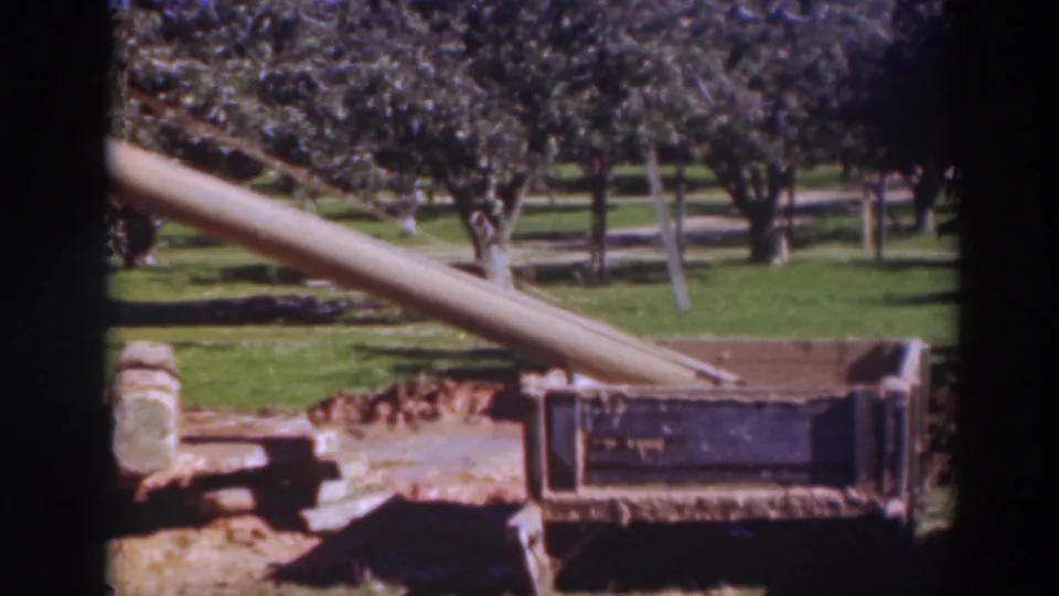 1937 Sacramento frame with the beam shifted diagonally across the view toward the dark metal frame, trees, grass, and rope still visible.