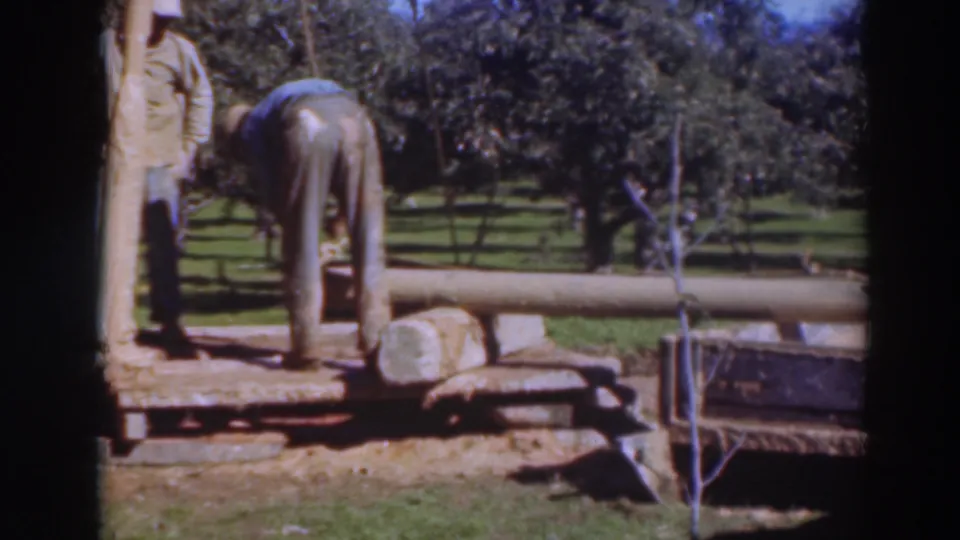 Home-movie frame from the stated 1937 Sacramento clip showing timber positioned near a portable saw rig and low trailer.