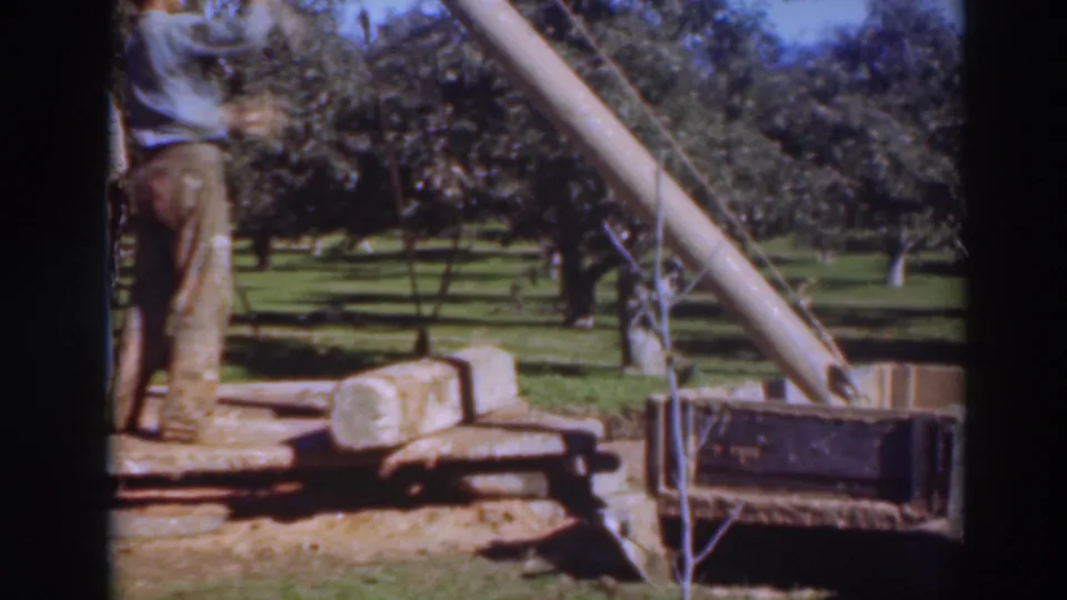 The 1937 Sacramento orchard scene shows a worker on a rough platform next to a cylindrical pipe and slanted boom assembly.