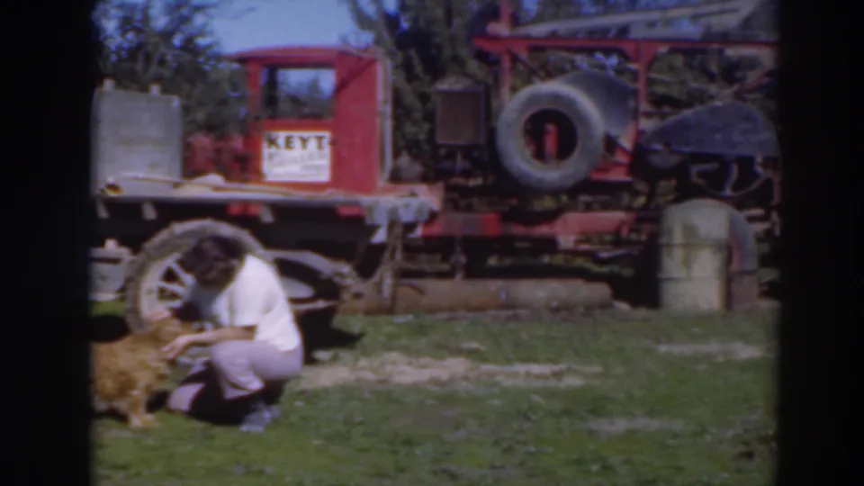 The final frame shows the woman still kneeling near the dog, with the red truck, spare tire, and yard objects in view.