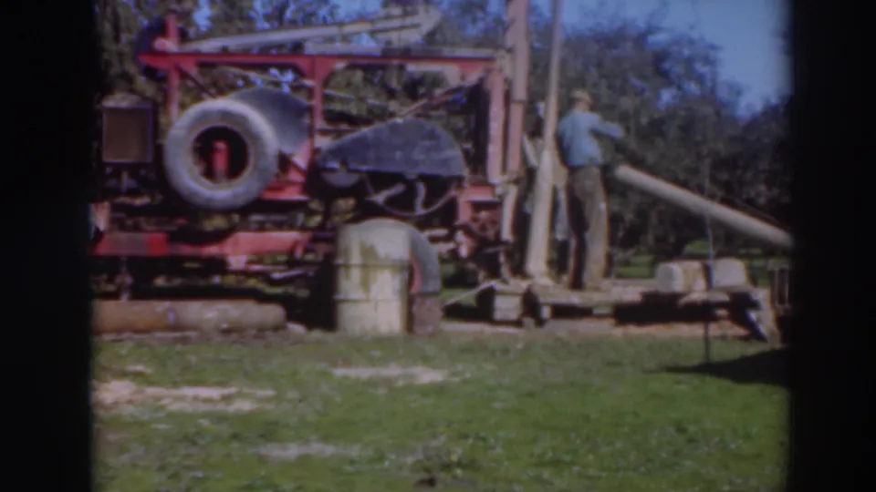 The 1937 Sacramento frame shows the red rig and spare tire with a standing worker at right and a partially visible crouching figure at left.