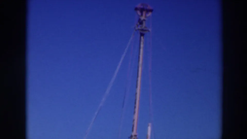 1937 Sacramento home-movie frame looking upward at a masthead, with rigging lines extending diagonally across the sky.