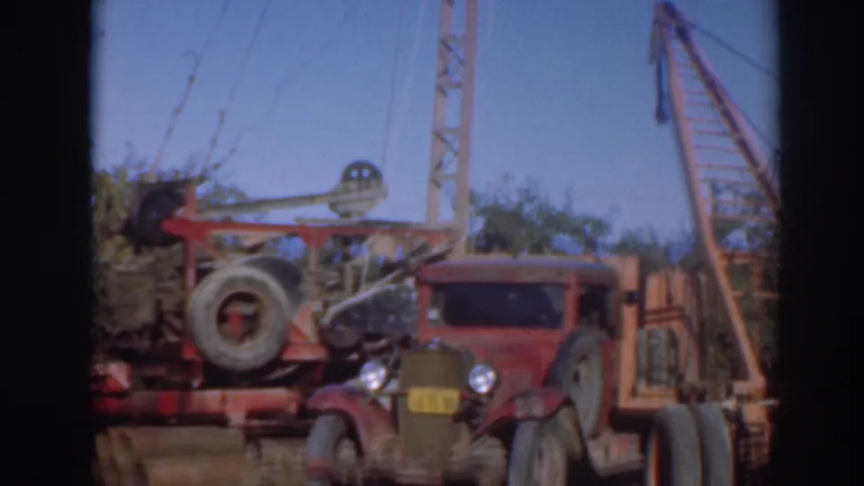 A red work truck sits next to crane equipment and timber stacks in 1937 Sacramento archival home-movie footage.
