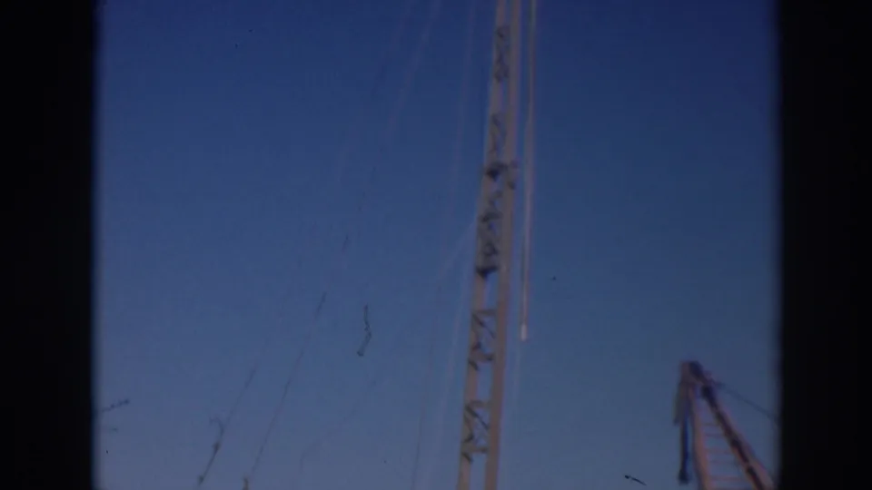 1937 Sacramento footage frame showing crane rigging, a lattice mast, and part of a red boom, softened by 8mm film grain.