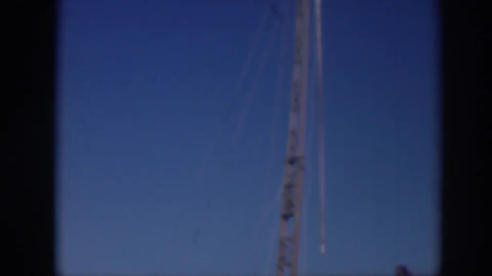 Final 1937 Sacramento frame with a crane mast, hanging rigging, and partial boom against an open blue sky.