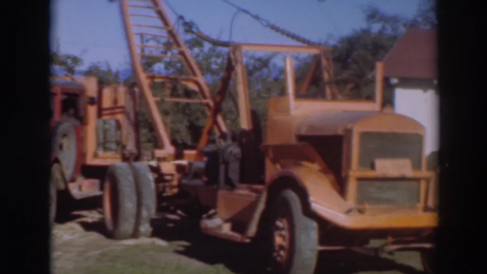 A later frame shows orange heavy equipment and the rear of a truck near a white building edge in the yard.
