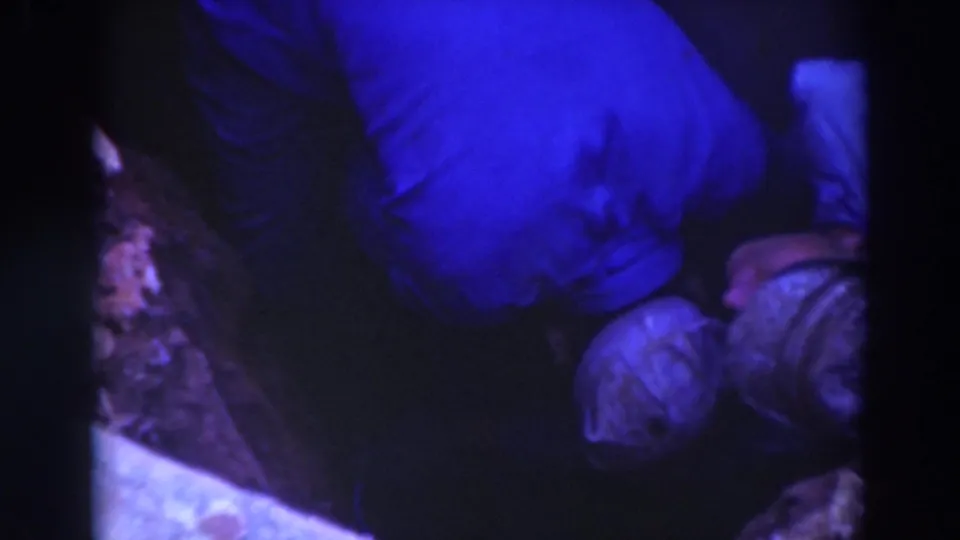 Close overhead 8mm view of a worker leaning into a Sacramento trench with another capped worker partly visible at the side.