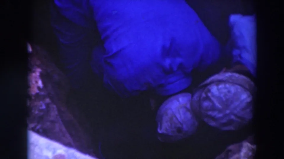 Overhead 1937 Sacramento 8mm view of workers in pale hats beside a blue-clad figure in a shadowed pit-like setting.