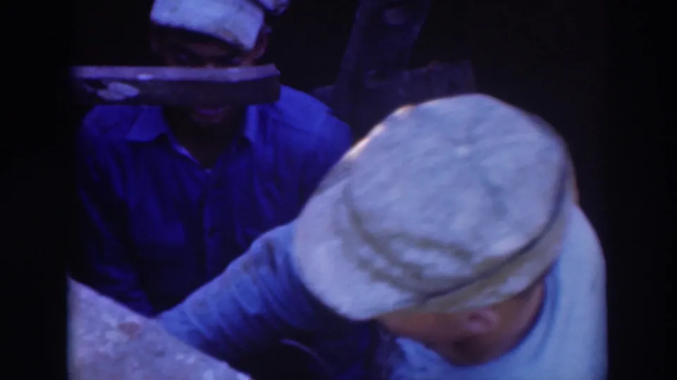 Sacramento 1937 home-movie frame showing workers clustered around a confined underground opening, partly obscured by a cap in the foreground.