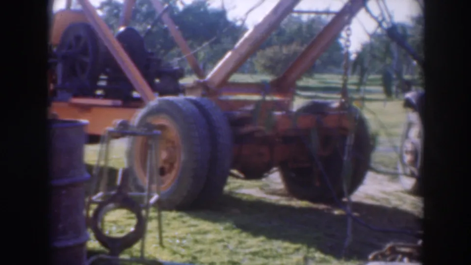 Orange heavy tow truck and work equipment parked in a sunlit Sacramento orchard area in 1937 footage.