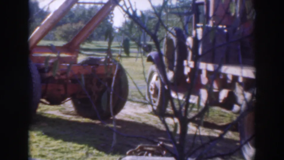 Final 1937 Sacramento home-movie frame with tow-truck rigging, rear wheel and neighboring work vehicle under orchard trees.