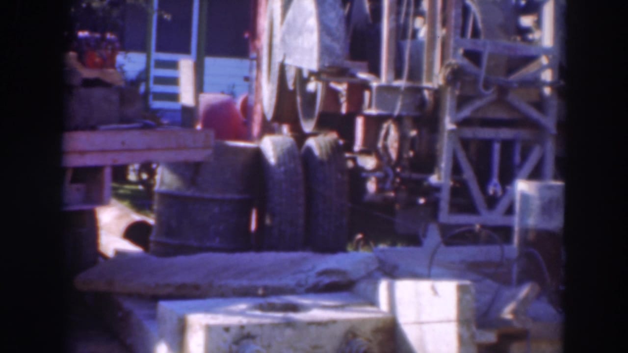 1937 Sacramento 8mm frame showing an outdoor industrial rig, tires, cables, and concrete components in bright daylight.