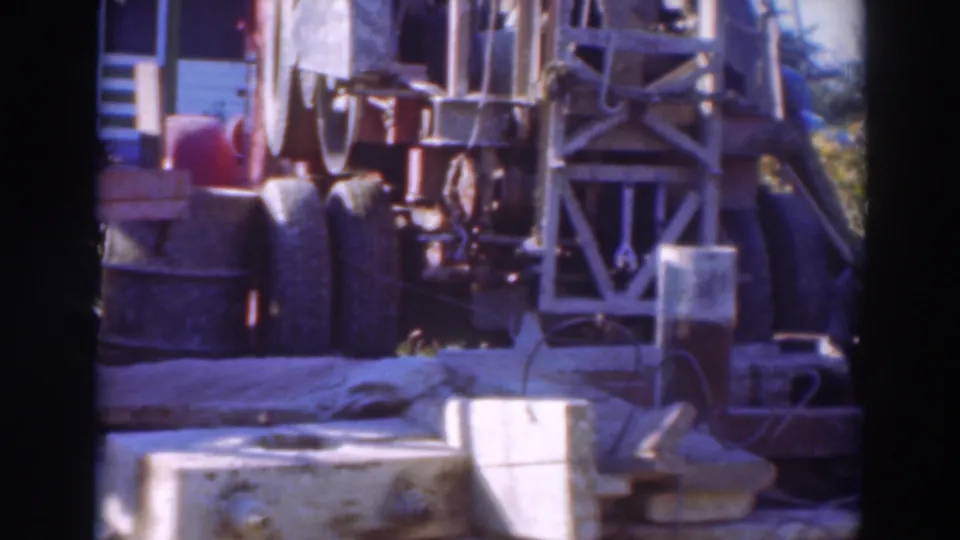 1937 Sacramento worksite view with a large rig, metal supports, tires, and concrete elements on 8mm film.