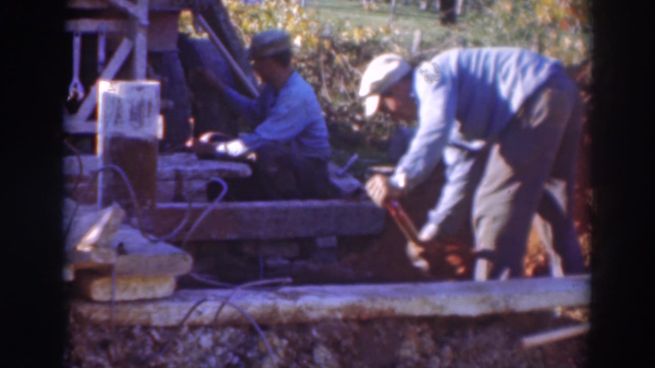 In Sacramento 1937 home-movie footage, two men in caps work outdoors beside a wooden platform and earth embankment.