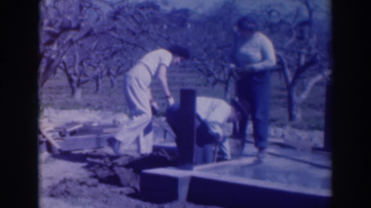 In 1937 Sacramento home-movie footage, three adults appear to work around a concrete slab or foundation in an orchard.
