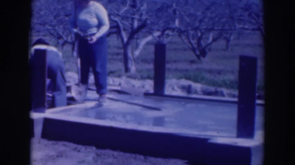 In the Sacramento orchard scene, one man stands with a shovel as another bends over the edge of the wet foundation.