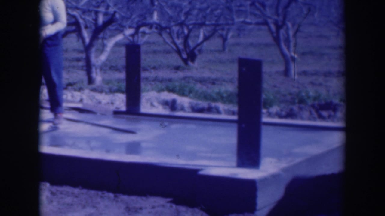 Concrete platform with upright posts, bare trees, and a partial standing figure at the left edge.