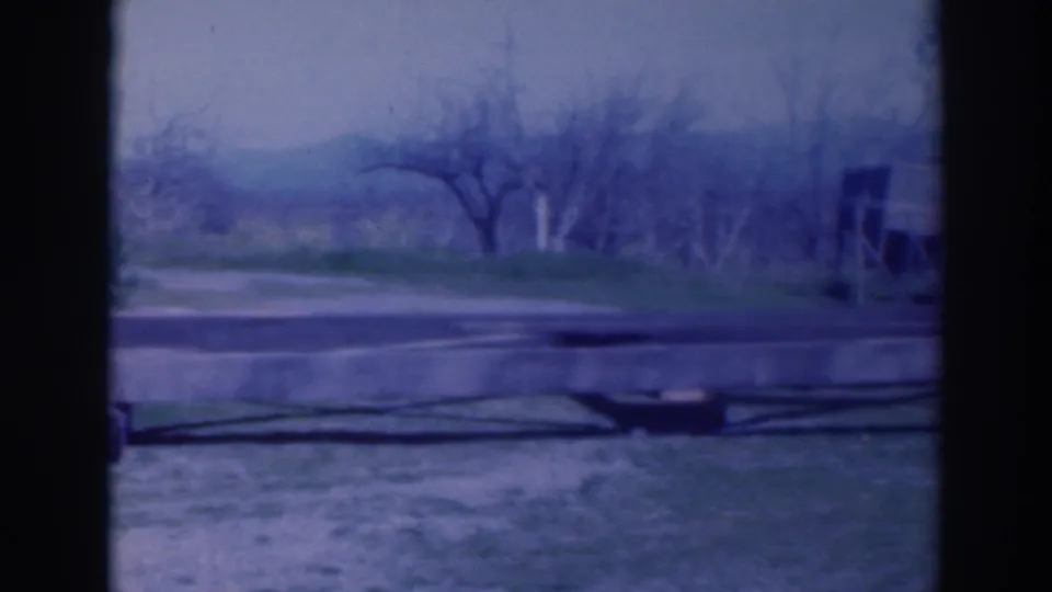 The final frame shows the slab or foundation area with a hose or pipe, orchard trees, and part of a nearby structure.
