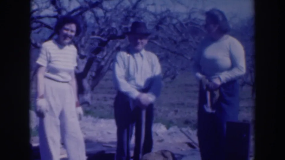 Two women and a man in 1937 Sacramento stand together in a garden area, with one person holding a long-handled tool.