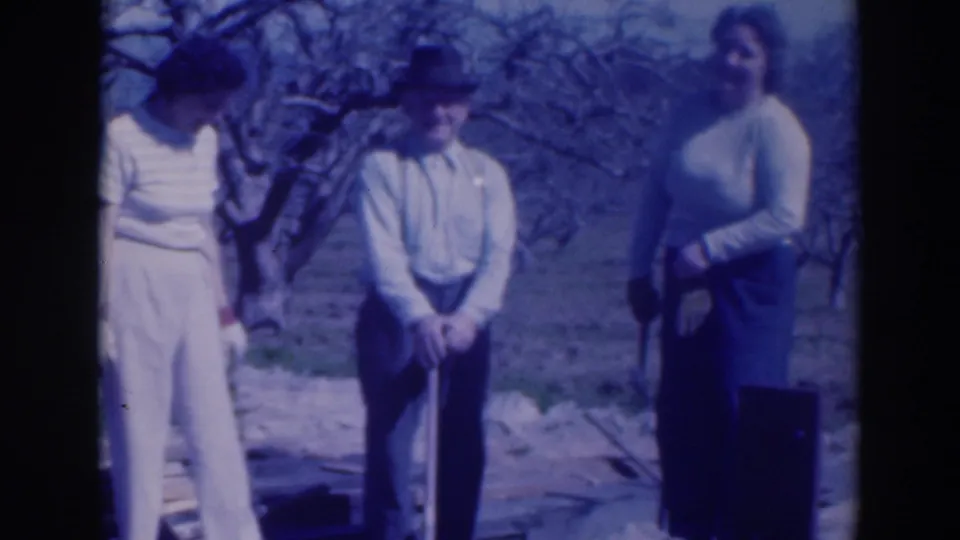 Three adults in 1937 Sacramento stand in an outdoor orchard or garden, with the central man smiling under a fedora.