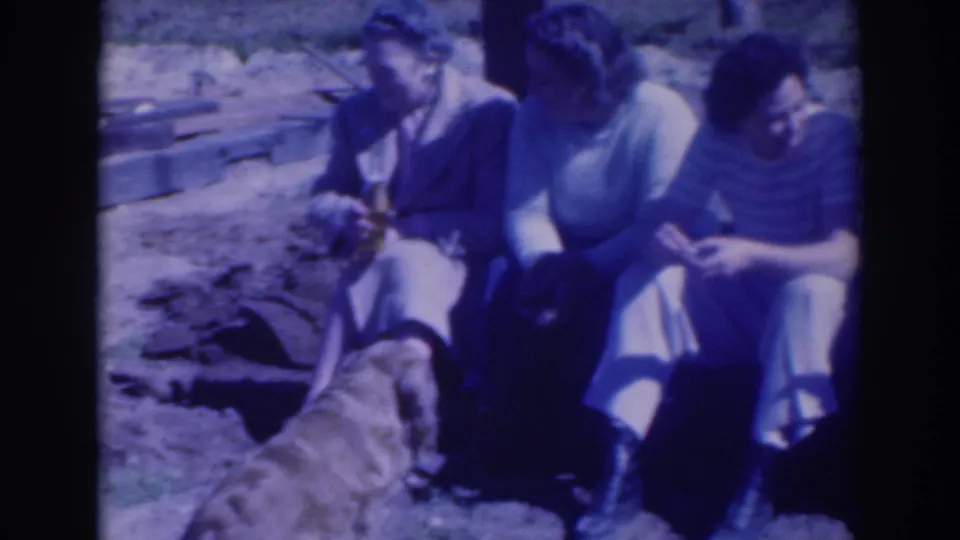 In the final frame, adults sit close together beside a dog near the excavation area, with tools or boards visible behind them.