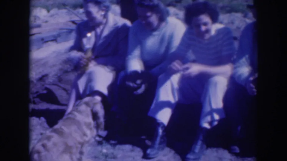 In 1937 Sacramento home-movie footage, several adults sit outdoors on grass while a dog stands near them.