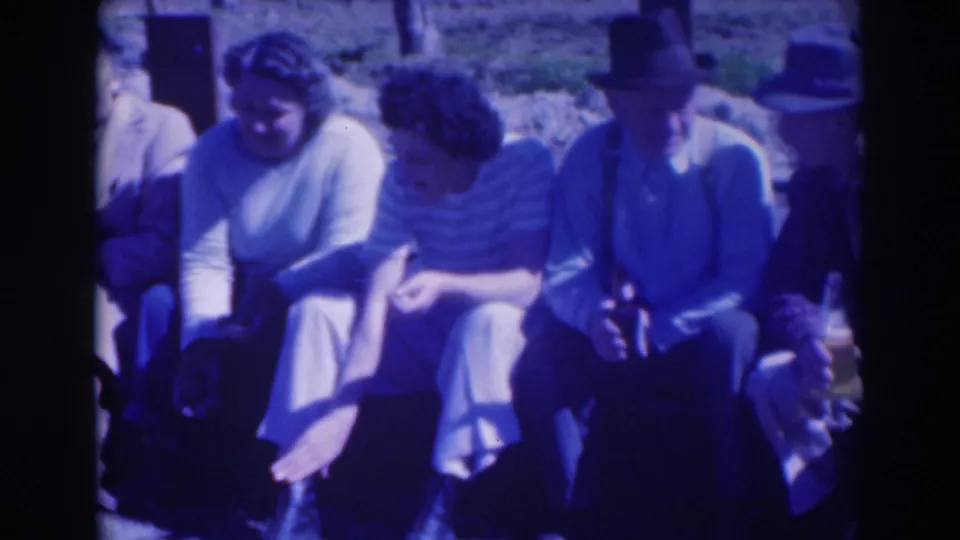 Three women and a hat-wearing man sit on the ground in 1937 Sacramento home-movie footage, with the left side partly cropped.