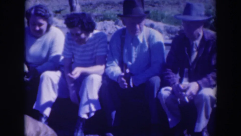 Adults sit side by side on a grassy slope in Sacramento, 1937, with two men in hats and women in sweaters visible.