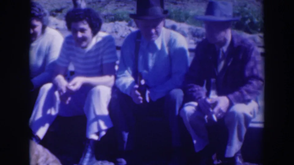 In 1937 Sacramento home-movie footage, four adults sit outdoors together, including two men in fedoras and a woman in a striped top.