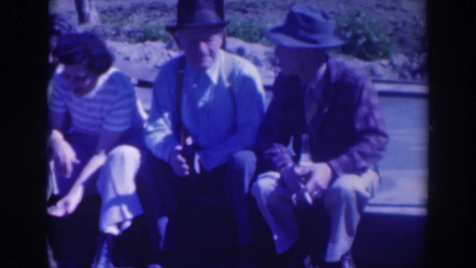 The Sacramento group remains seated outdoors, with two hat-wearing men centered and one woman partly cropped at frame left.