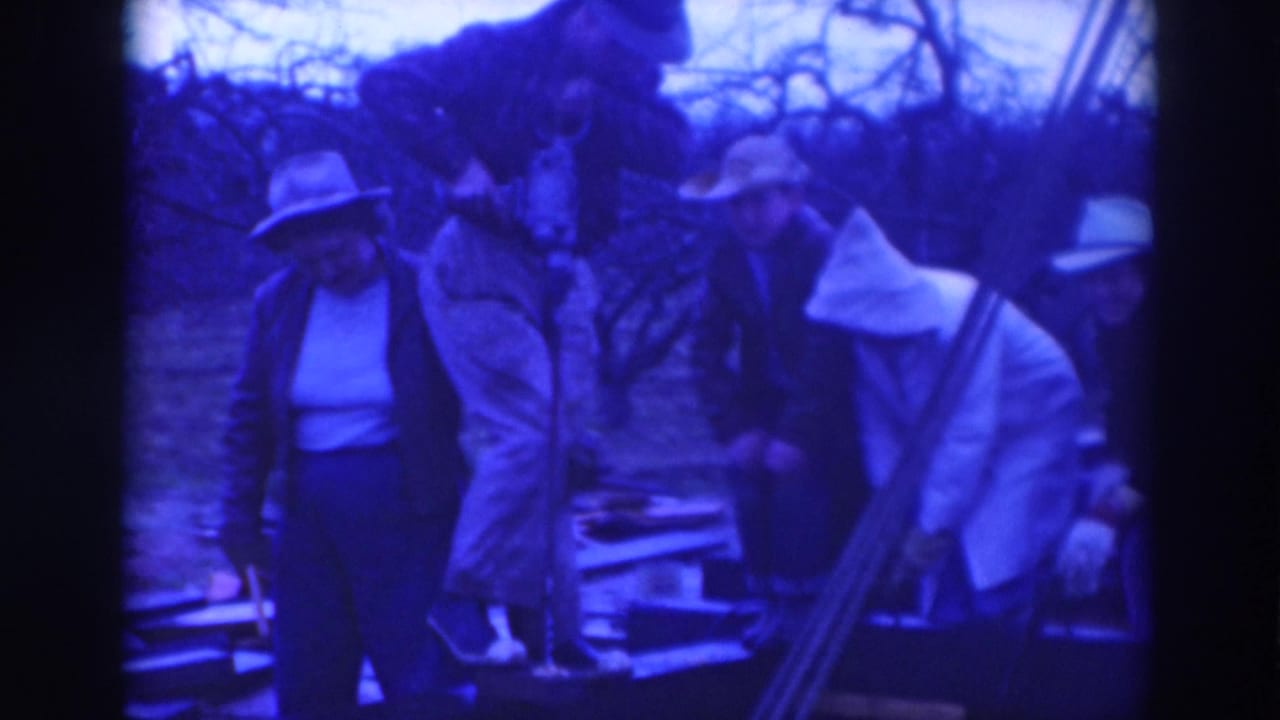 Adults stand around a work area as one person bends near rails or boards.