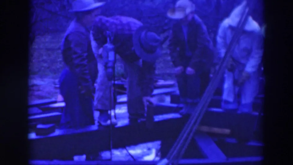 Adults in hats bend and stand around a wooden platform in 1937 Sacramento, with one figure appearing to work at the surface.