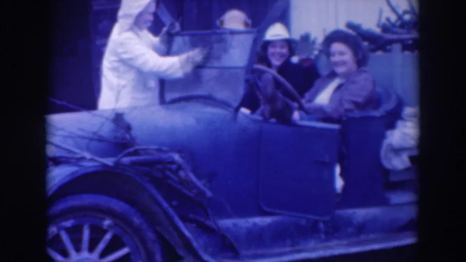 In the 1937 Sacramento home-movie frame, two women in hats sit in the car while another person appears to wash or handle the side panel.