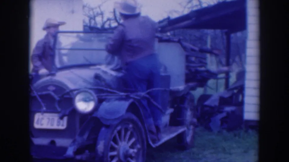 In the Sacramento yard scene, one man turns toward the windshield of the open car while another remains near the front fender.