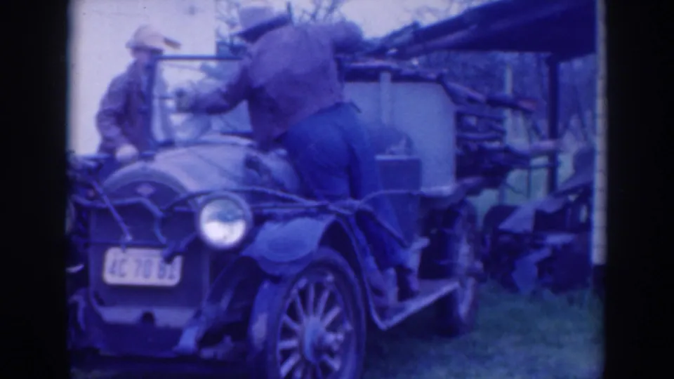 A man standing on the running board wipes or reaches across the windshield of the 1937 Sacramento vintage car as another man stands nearby.