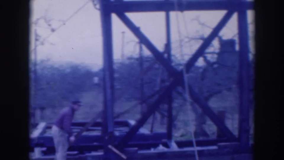 A hat-wearing worker moves along the base of the large wooden framework in the 1937 Sacramento home-movie footage.